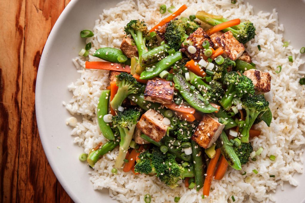 Mixed vegetables and sesame seeds on a bed of white rice, seasoned with green onion and teriyaki sauce.